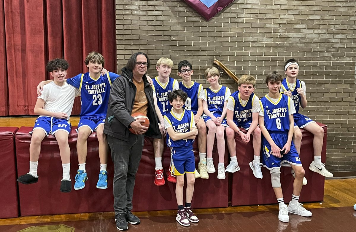 A St. Joseph's Yorkville boys basketball team with their coach on the stage before a game.