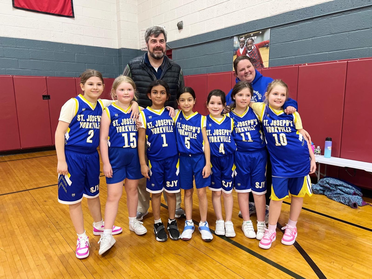 A St. Joseph's Yorkville girls basketball team with their coaches at an away gym.